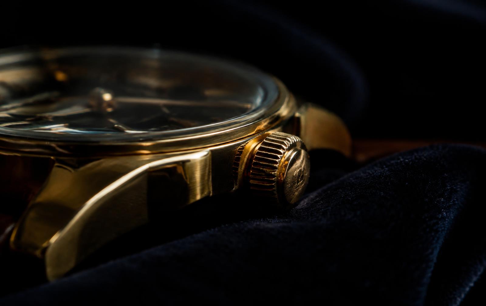 Gold watch case and crown resting on velvet